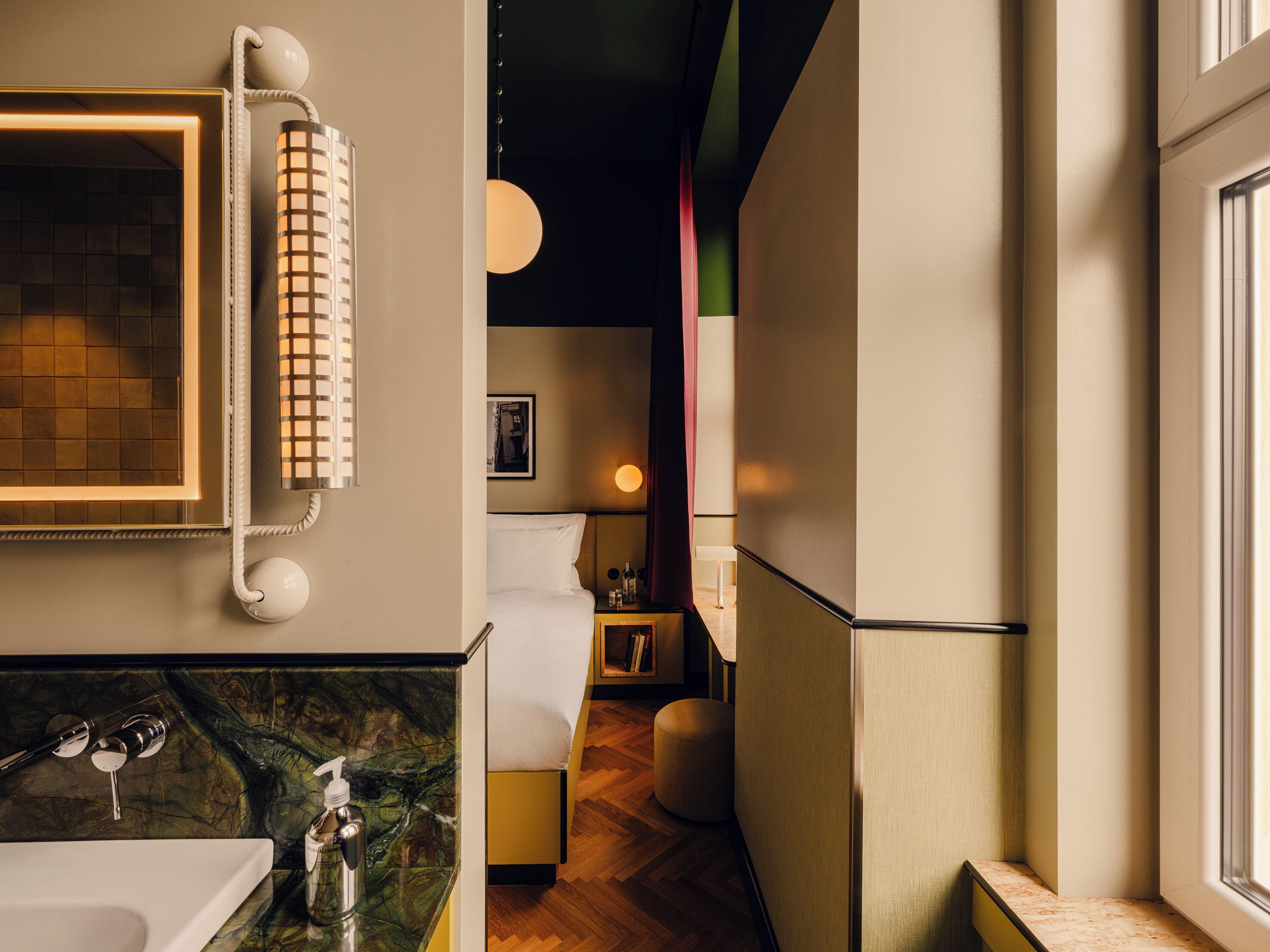 Ein modernes Badezimmer mit Marmorplatte, einem weißen Waschbecken, einem Spiegel mit Handtuch und einem Nachttisch mit Lampe.
