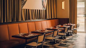 A restaurant with a checkered floor, leather booth seating, and a large abstract painting on the wall.