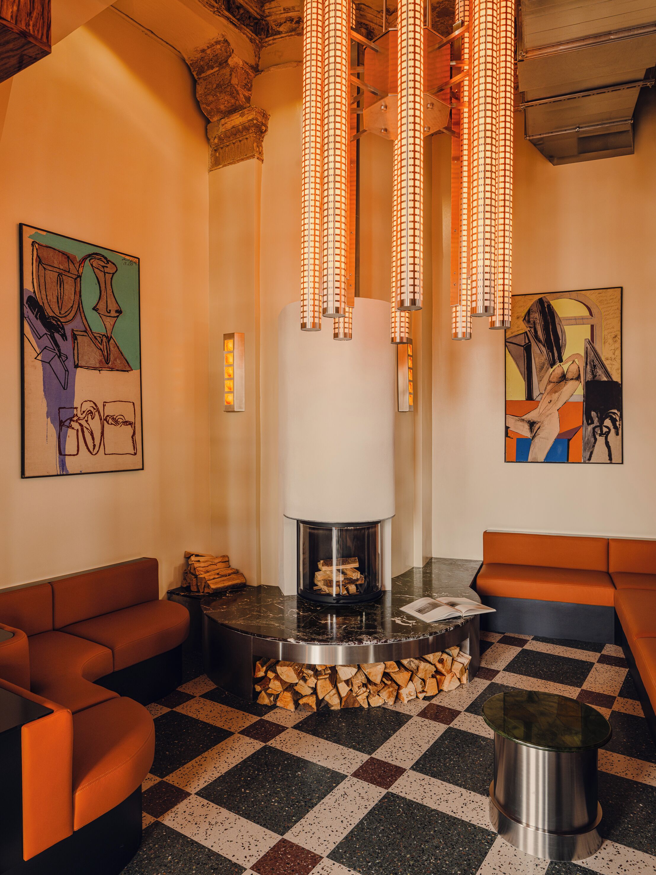 A modern interior with a fireplace, orange seating, and abstract art.