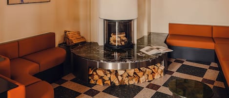 Un interior moderno con chimenea, asientos naranjas y arte abstracto.