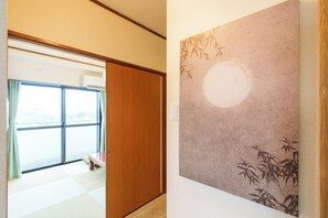 A room with a sliding door leading to a balcony, a wall with a bamboo pattern, and a checkered floor.