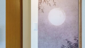 A hallway with a wooden door, a wall-mounted light fixture, and a framed artwork depicting bamboo and a moon. - Tranquil Riverside Home - 4min Train to Skytree & Asakusa (墨田区東墨田2丁目)