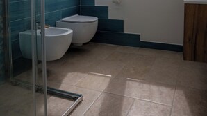 A bathroom with a glass shower enclosure, a toilet, a bidet, and a window with blinds. - Super cosy apartment near the sea for 6/8 people (Follonica)