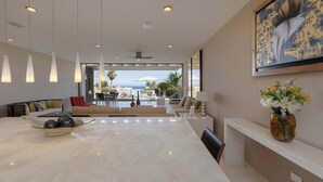 A spacious living area with a marble coffee table, a red sofa, and a dining area with a large table. - 6BR Luxe Villa w/ Infinity Pool & Ocean Views (Cabo San Lucas)