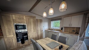 Cocina compacta con muebles de madera, horno empotrado y comedor con mesa y sillas.