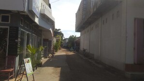 A narrow street with buildings on either side, a signboard, and a bicycle parked on the right.