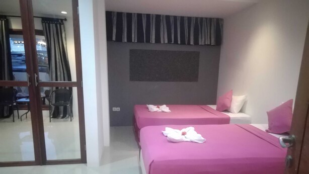 A hotel room with two beds, a large window with curtains, a flat-screen TV, and a seating area with chairs and a table.