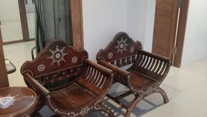 Two wooden chairs with intricate designs, a small table, and a door in the background.