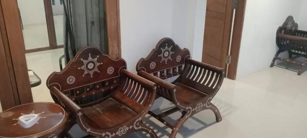 Two wooden chairs with intricate designs, a small table, and a door in the background. - EXPRESS O 91581 Starla Spa & Home Stay (Gili Trawangan)