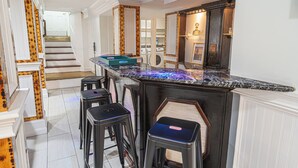 A kitchen with a marble countertop, bar stools, and a built-in oven.