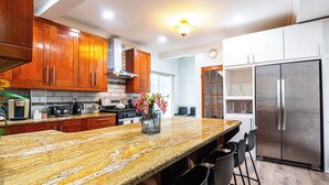 A modern kitchen with granite countertops, stainless steel appliances, wooden cabinets, and a central island with bar stools.