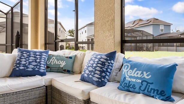 A covered outdoor seating area with wicker furniture and cushions featuring nautical designs.