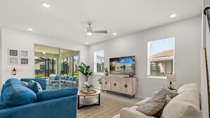 A spacious living room with a blue sofa, a beige sofa, a coffee table, and a TV on a wooden cabinet.