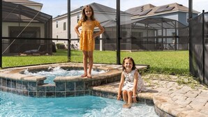 A swimming pool with a hot tub, surrounded by a covered patio area.