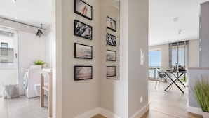 A modern kitchen with a washing machine, a dining area with a table and chairs, and a balcony with a view.