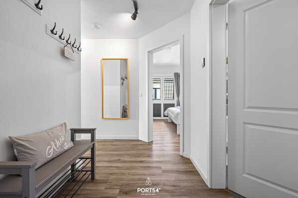 A hallway with a bench, a mirror, and a door leading to a bedroom. - Küstenglück - Shower room, covered balcony, garden furniture, TV, parking space (Damp)
