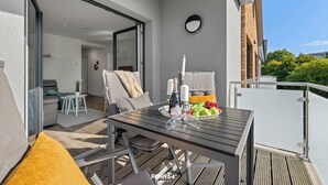 A balcony with a wooden table, chairs, and a bowl of fruit. - Küstenglück - Shower room, covered balcony, garden furniture, TV, parking space (Damp)