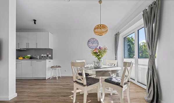 Une cuisine moderne avec des meubles blancs et un coin repas comprenant une table et des chaises en bois.