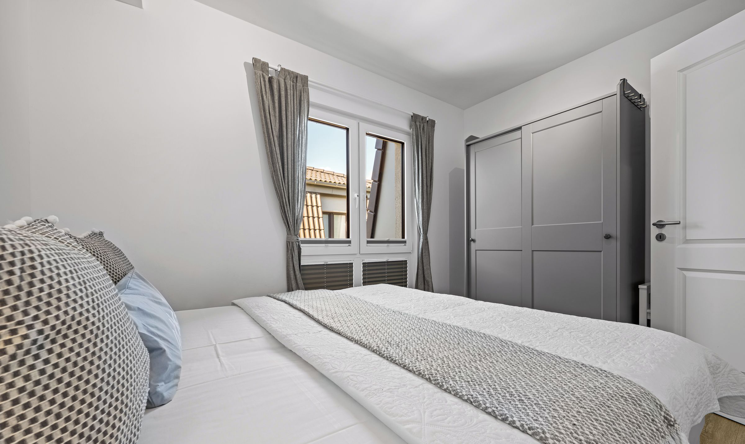 Une chambre à coucher avec un lit, des rideaux, une armoire et une fenêtre.