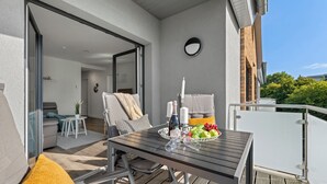 Un balcon avec une table en bois, des chaises et un saladier rempli de fruits.