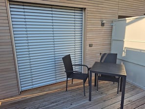 Un patio con una mesa y sillas, un portón corredero y una lámpara fijada a la pared.