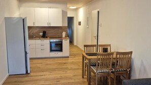 Een knus leefruimte met kitchenette, eethoek en een bank.