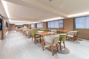 A spacious dining area with multiple tables and chairs, a kitchen in the background, and large windows providing natural light. - Ji Hotel Guangzhou Shayuan Metro Station (Guangzhou)