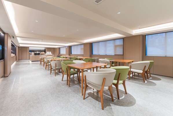 A spacious dining area with multiple tables and chairs, a kitchen in the background, and large windows providing natural light. - Ji Hotel Guangzhou Shayuan Metro Station (Guangzhou)