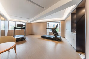 A modern room with a treadmill, a chair, and a view of the city through large windows. - Ji Hotel Guangzhou Shayuan Metro Station (Guangzhou)
