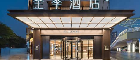 A hotel entrance with a revolving door, illuminated signage, and a modern architectural design.