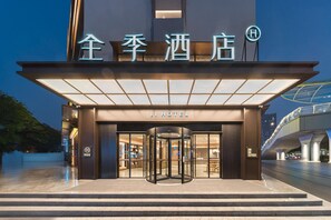 A hotel entrance with a revolving door, illuminated signage, and a modern architectural design. - Ji Hotel Guangzhou Shayuan Metro Station (Guangzhou)