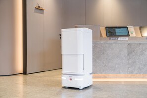 A white, modern, self-service kiosk with a digital display screen, situated in a clean, minimalistic lobby area with a marble floor and neutral-toned walls. - Ji Hotel Guangzhou Shayuan Metro Station (Guangzhou)