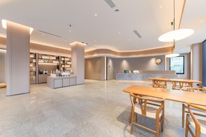 A modern hotel lobby with a central reception desk, seating area, and a kitchenette. - Ji Hotel Guangzhou Shayuan Metro Station (Guangzhou)