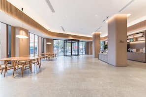 A spacious lobby with a roundabout seating area, large windows, and a modern kitchen visible in the background. - Ji Hotel Guangzhou Shayuan Metro Station (Guangzhou)
