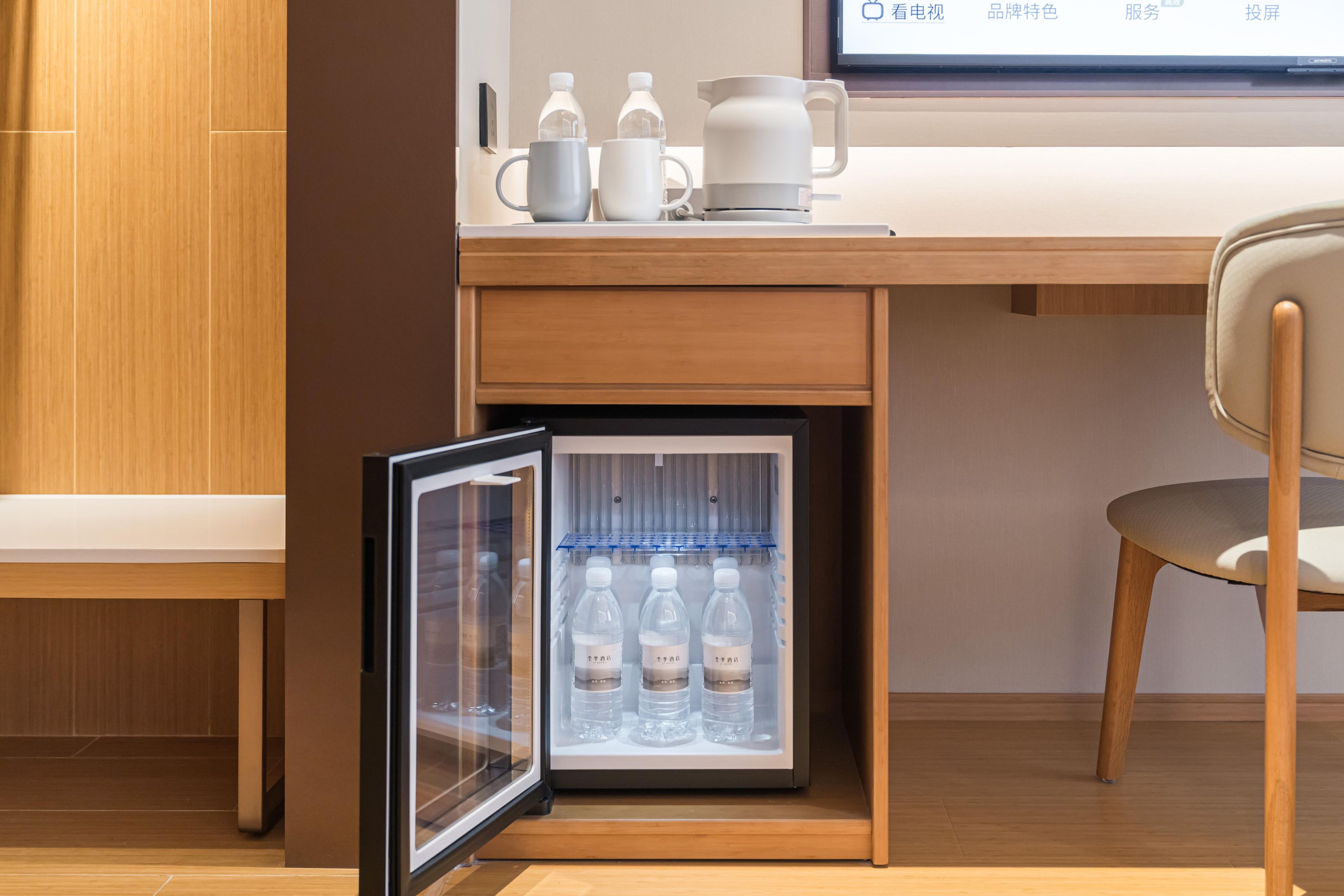 Un refrigerador compacto con puerta de vidrio, que contiene varias botellas de agua.