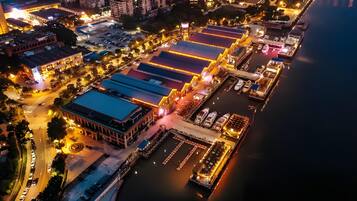 An aerial view of a waterfront area with buildings, a marina, and a road.