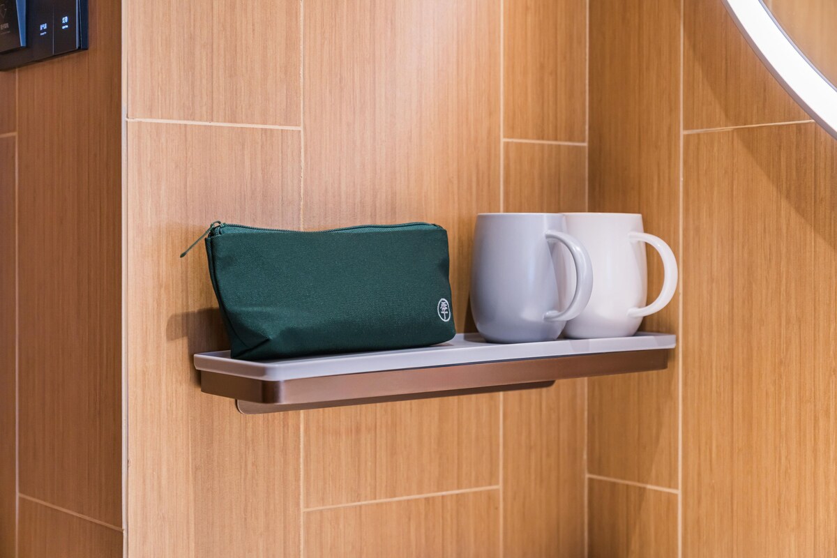 A shelf with a green pouch and a white mug against a wooden wall.
