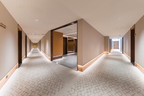 A long, narrow hotel corridor with a patterned carpet, recessed lighting, and a mirrored wall reflecting the corridor. - Ji Hotel Guangzhou Shayuan Metro Station (Guangzhou)