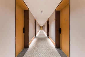 A long, narrow hotel corridor with wooden doors on both sides and a patterned floor. - Ji Hotel Guangzhou Shayuan Metro Station (Guangzhou)