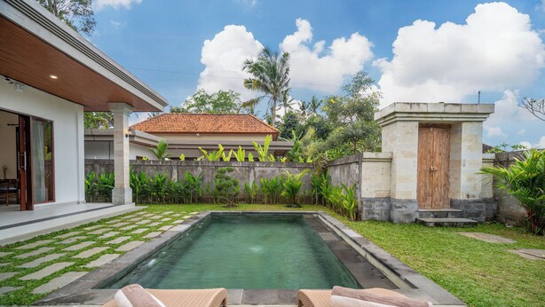 A pool area with lounge chairs and a stone wall. - Pertibi Private Villa (Ubud)