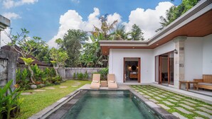 A swimming pool with two lounge chairs, a wooden bench, and a small table. - Pertibi Private Villa (Ubud)