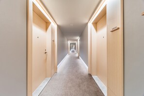 A long, narrow hallway with wooden doors on either side, leading to a series of rooms. - Ji Hotel Guangzhou Jiangnanxi Metro Station (Guangzhou)