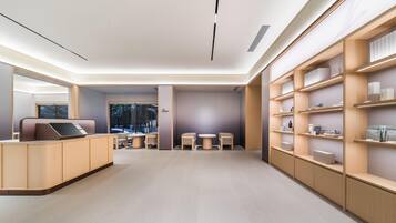 A modern interior with a reception desk, seating area, and shelving units.