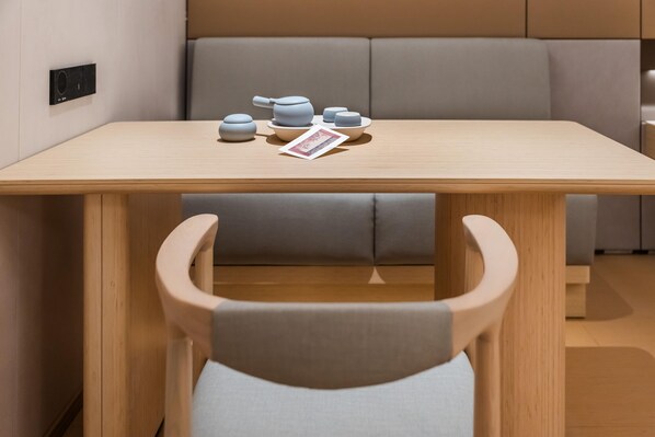 A modern dining area with a wooden table, grey cushioned seating, and a small tea set. - Ji Hotel Guangzhou Jiangnanxi Metro Station (Guangzhou)