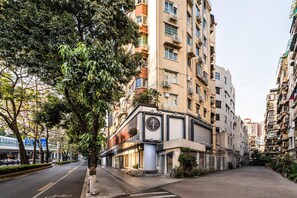 A multi-story building with a prominent sign featuring a symbol and text. - Ji Hotel Guangzhou Jiangnanxi Metro Station (Guangzhou)
