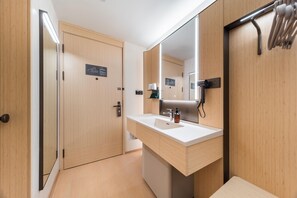 A modern bathroom with wooden walls, a large mirror, a sink, and a towel rack. - Ji Hotel Guangzhou Jiangnanxi Metro Station (Guangzhou)