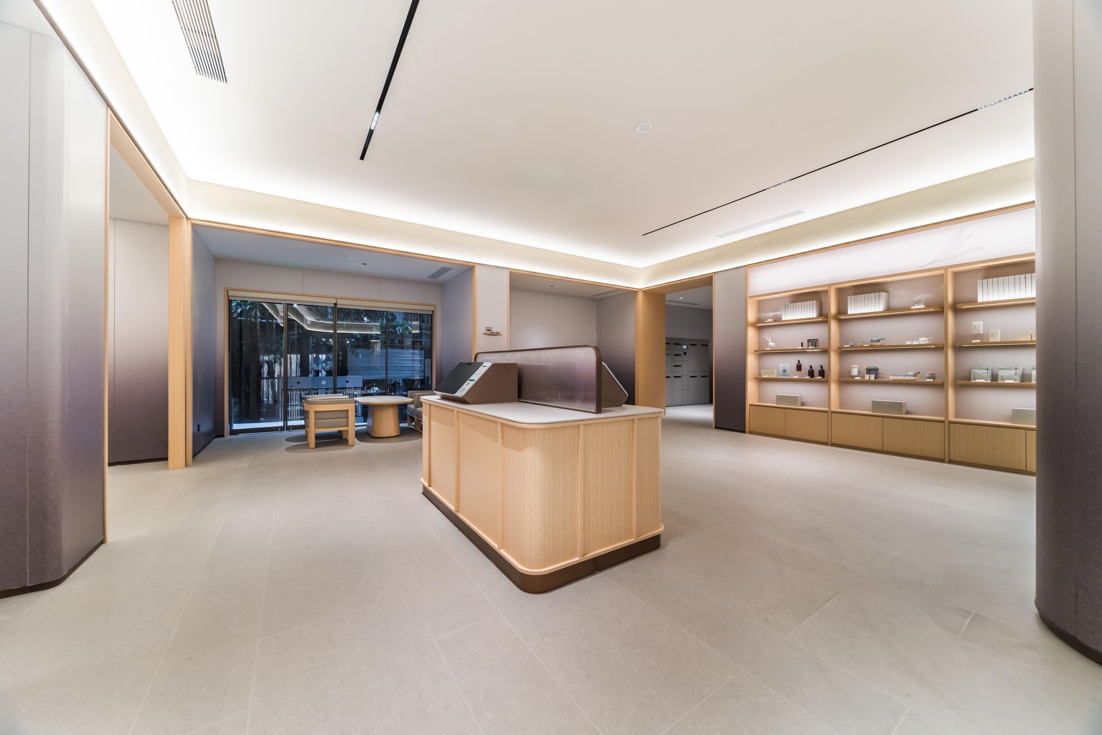 A modern hotel lobby with a reception desk, seating area, and a display of amenities.
