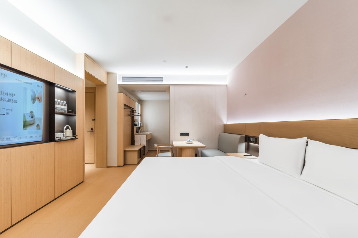A modern hotel room with a large bed, a desk, and a television.