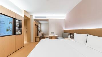 A modern hotel room with a large bed, a desk, and a television.