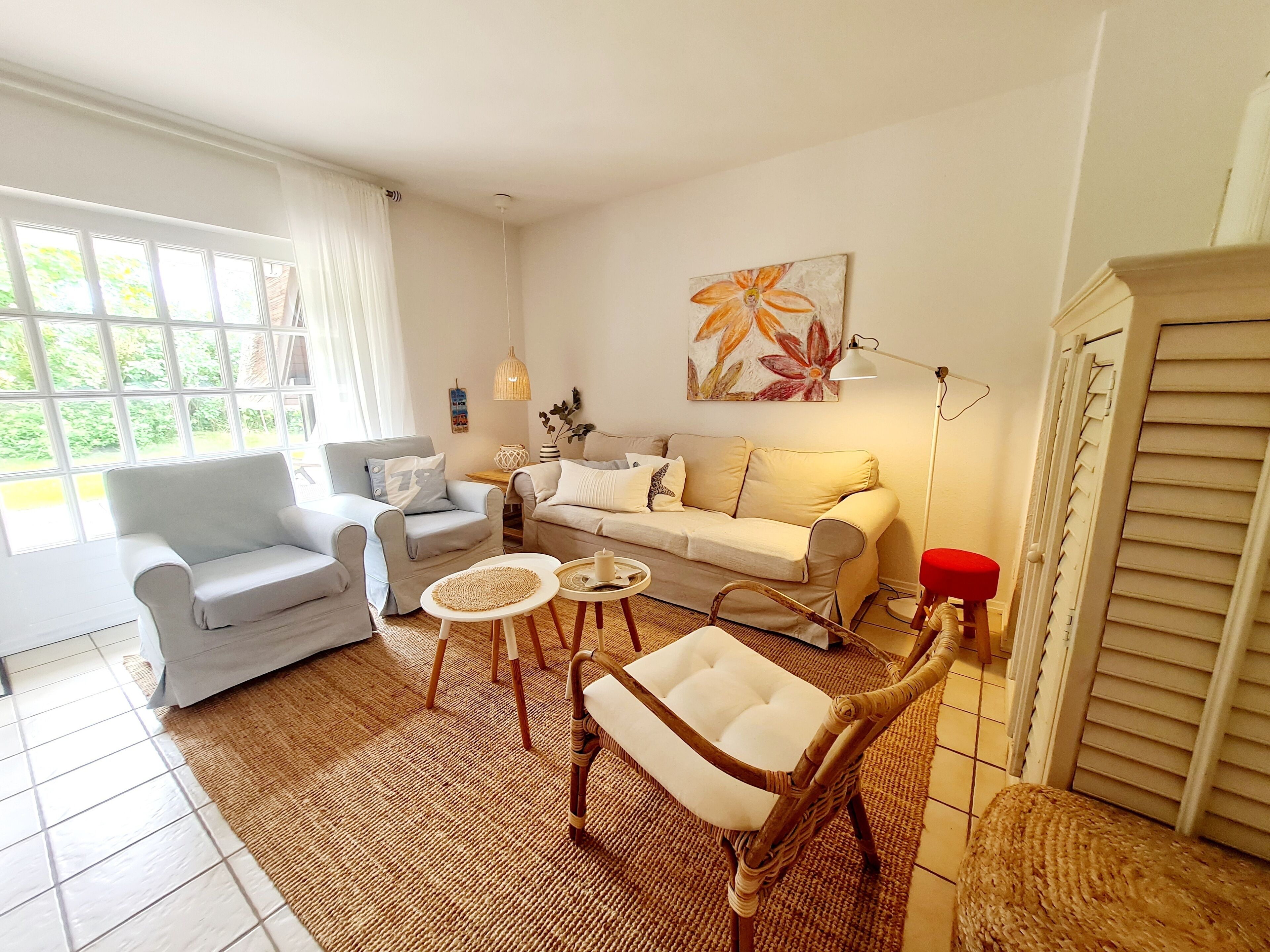 Un salon comprenant un canapé, un fauteuil, une table basse et une chaise en osier.